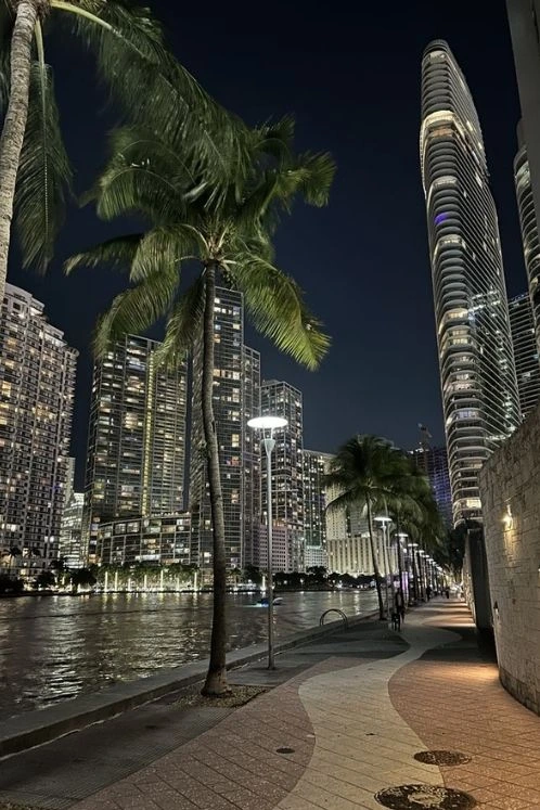 Paseo ribereño en Brickell, Miami, con torres residenciales iluminadas de noche.