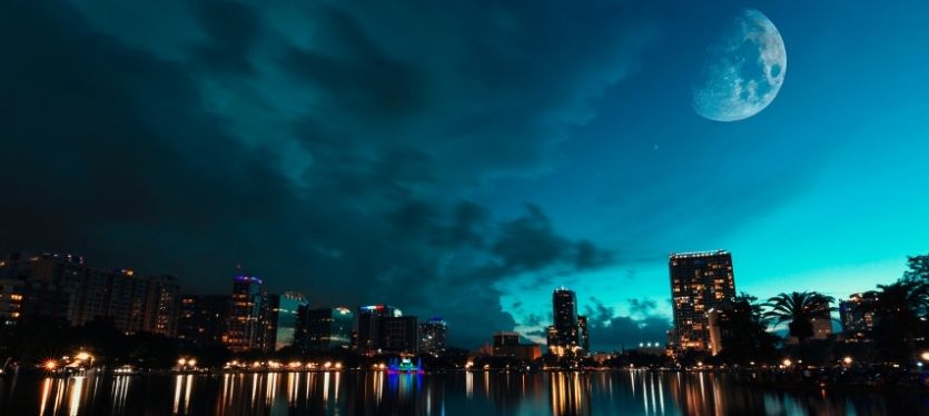La luna resplandece sobre la ciudad nocturna, iluminando edificios y calles con su luz suave