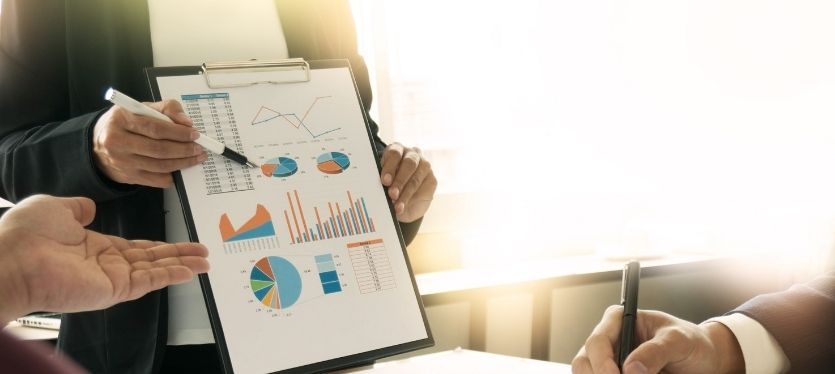 A group of business people reviewing a clipboard with graphical data and charts