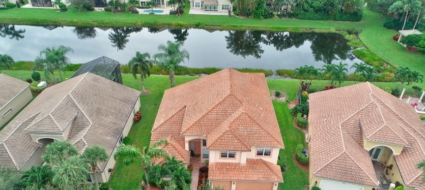 Imagen aérea de un barrio residencial con casas y un estanque, mostrando la disposición de las calles y áreas verdes