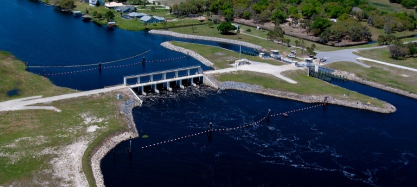 Imagen aérea de una presa en un río, destacando su diseño y el paisaje circundante