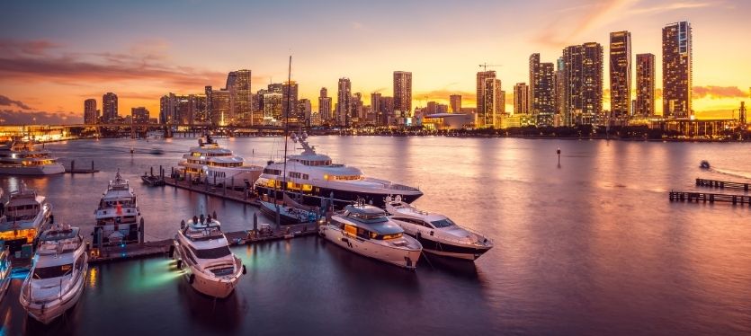 Barcos en el muelle al atardecer, con un skyline de ciudad de fondo