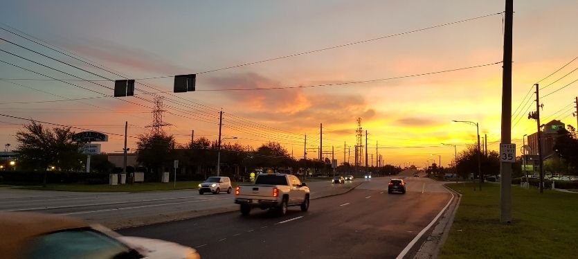 Vista de un atardecer en la carretera, con vehículos transitando bajo un cielo colorido
