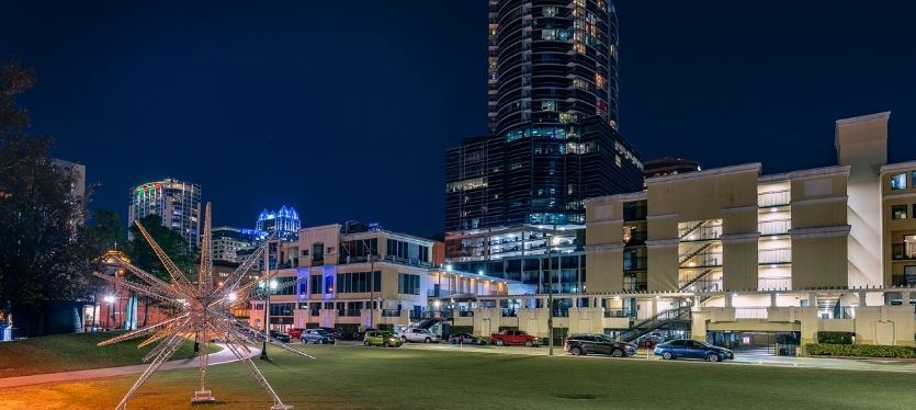 Vista nocturna de un horizonte urbano con una escultura destacada en el primer plano