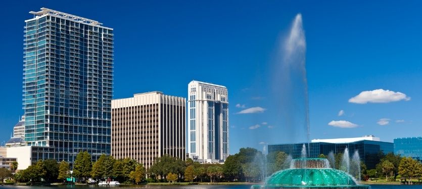 A city fountain in front of towering buildings, creating a vibrant urban scene with water splashing in the sunlight