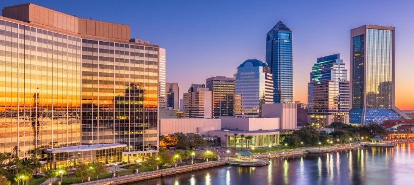 Florida, al atardecer, con edificios iluminados y un cielo anaranjado y púrpura