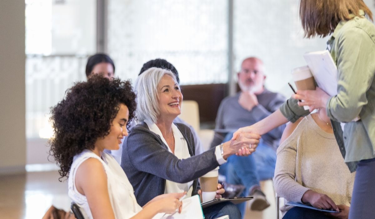Una mujer estrechando la mano de otra mujer durante una reunión hoa