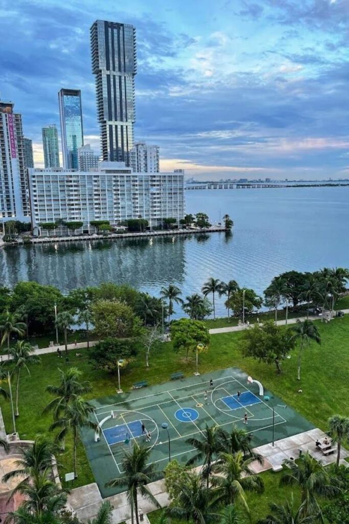 Vista de una cancha de baloncesto con un paisaje Edgewater de fondo, destacando la silueta de la ciudad