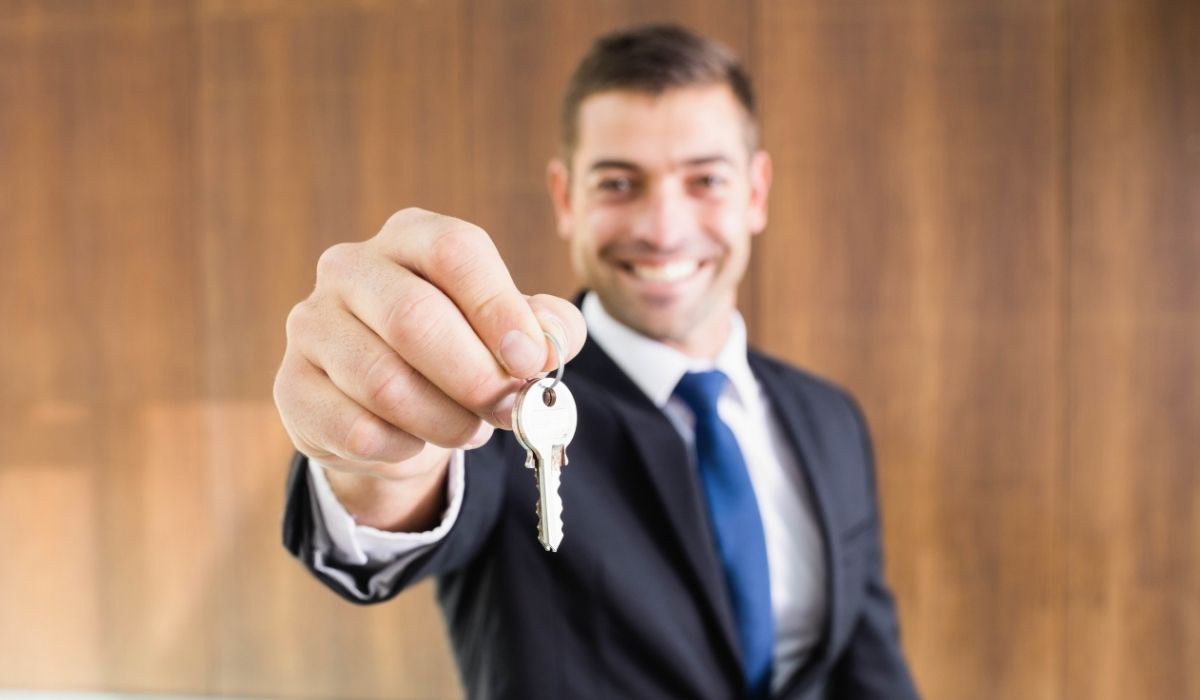 Hombre de traje sosteniendo una llave, sonriendo y mirando hacia la cámara dando opciones de financiamiento