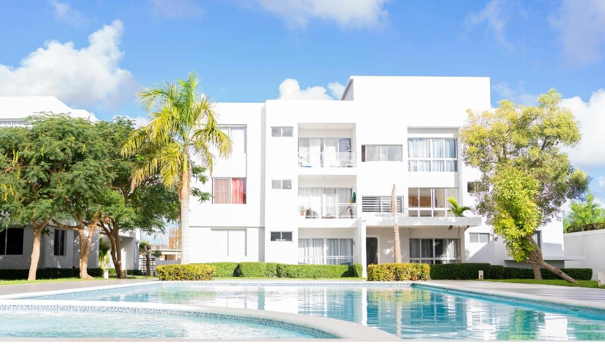 Apartamento blanco rodeado de palmeras y una piscina refrescante