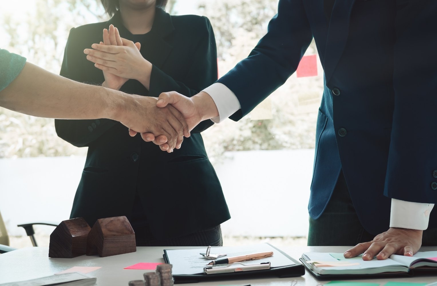 Personas de negocios estrechando manos sobre una mesa, simbolizando acuerdos en inversiones en Florida