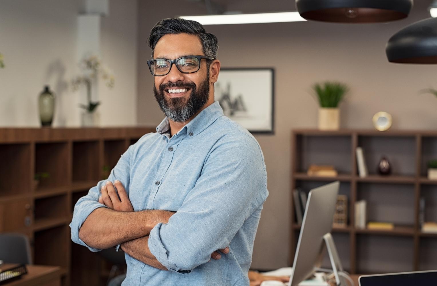 A man with glasses and a beard stands in front of his computer, focused on his work related to starting an LLC in Florida.
