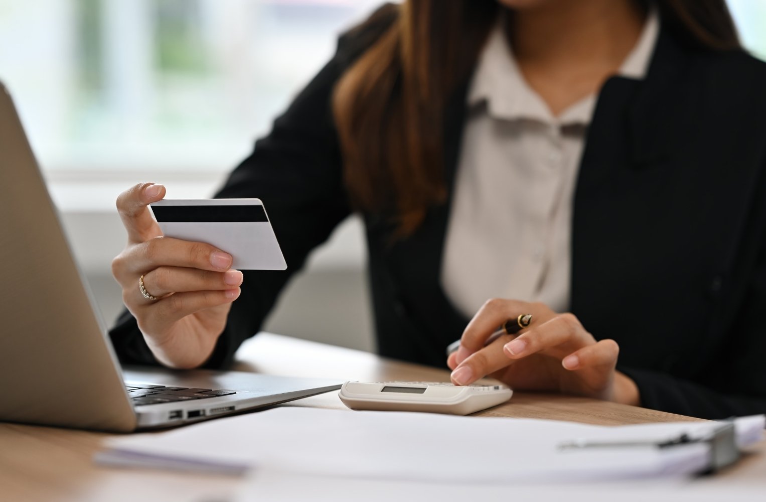 Mujer en traje de negocios sosteniendo una tarjeta de crédito, lista para transferir dinero de LATAM a Florida