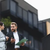 Dos profesionales de negocios de pie frente a un edificio, discutiendo sobre hipotecas en Florida para extranjeros