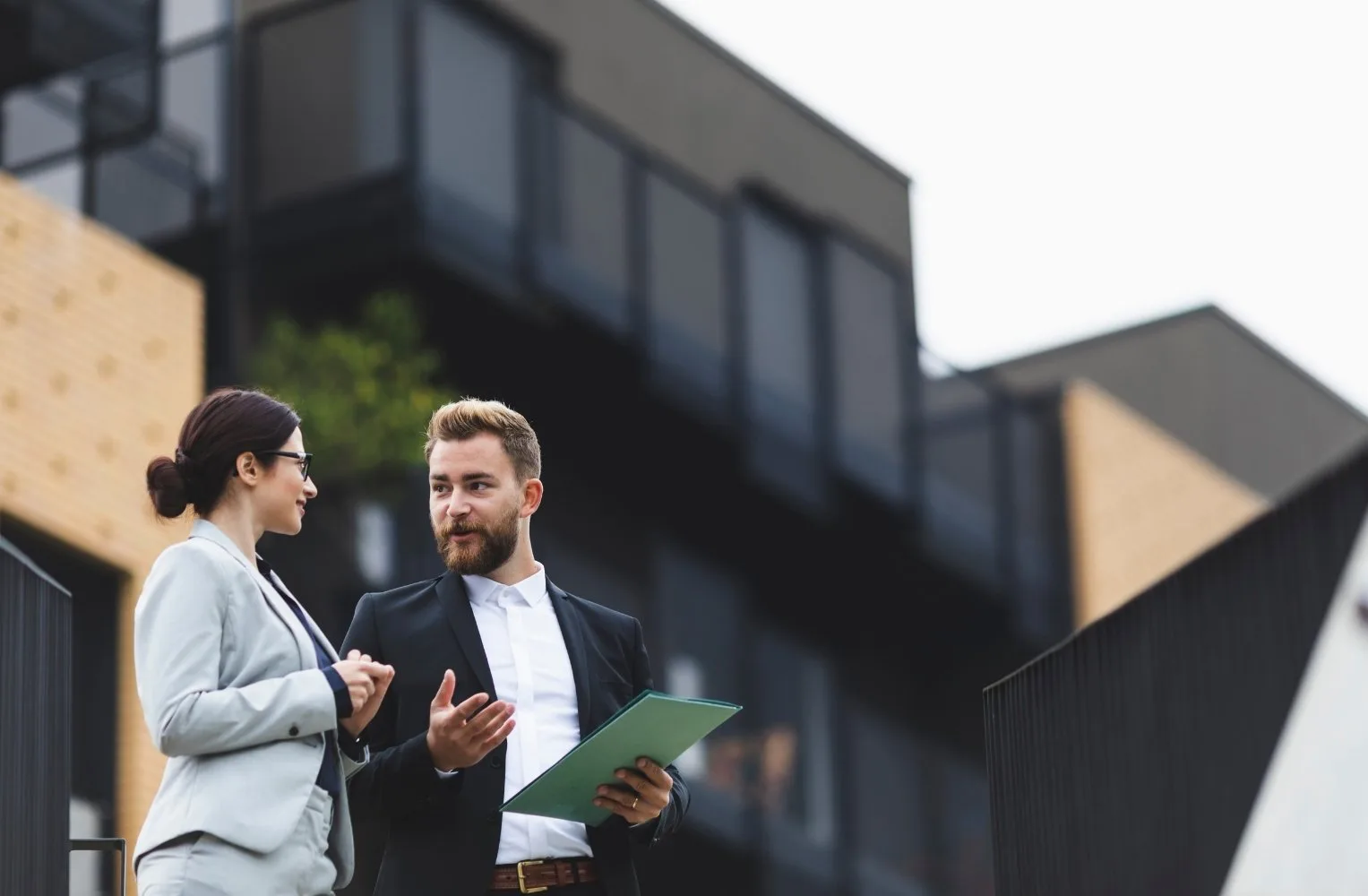 Dos profesionales de negocios de pie frente a un edificio, discutiendo sobre hipotecas en Florida para extranjeros