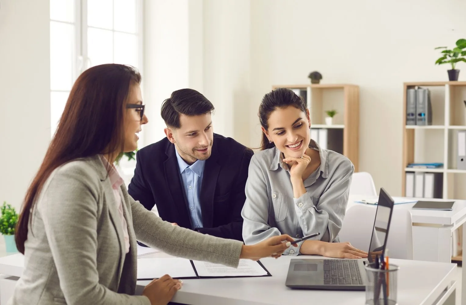 Tres profesionales discuten en una mesa con un laptop, enfocados en hipotecas en Florida para extranjeros.