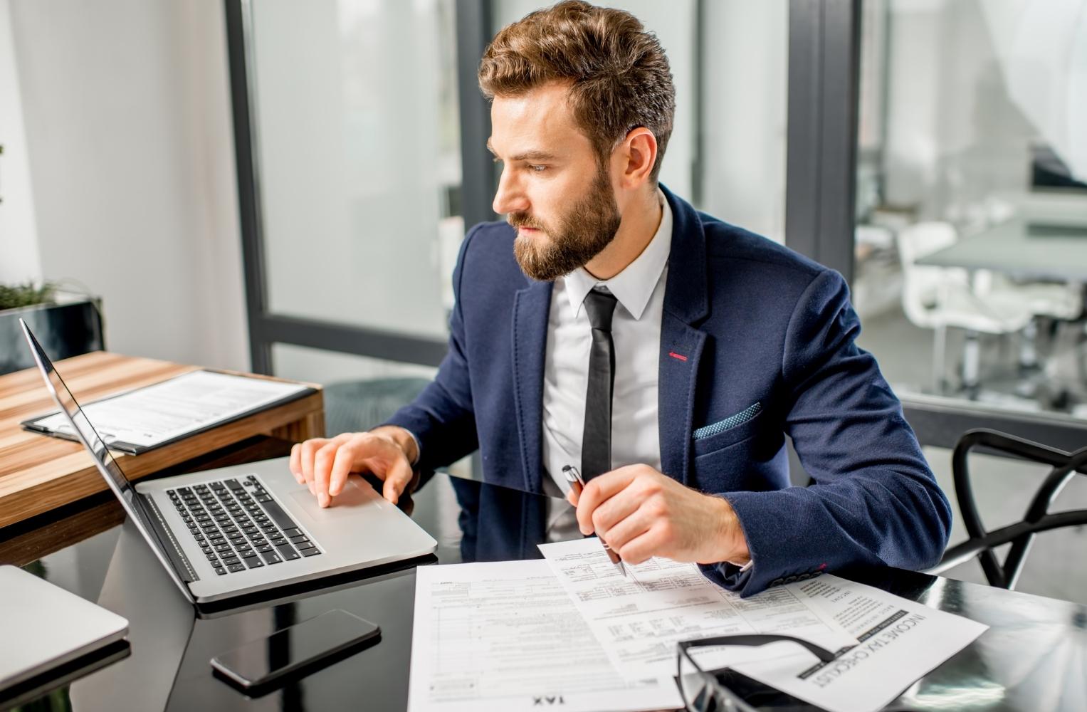 Man in a suit working on his laptop, focused on FIRPTA information for investors.