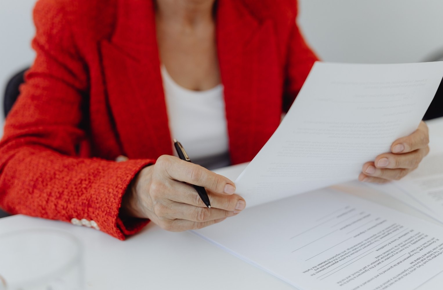 Mujer con chaqueta roja sostiene un papel, participando en el proceso de cierre de propiedades en Florida.