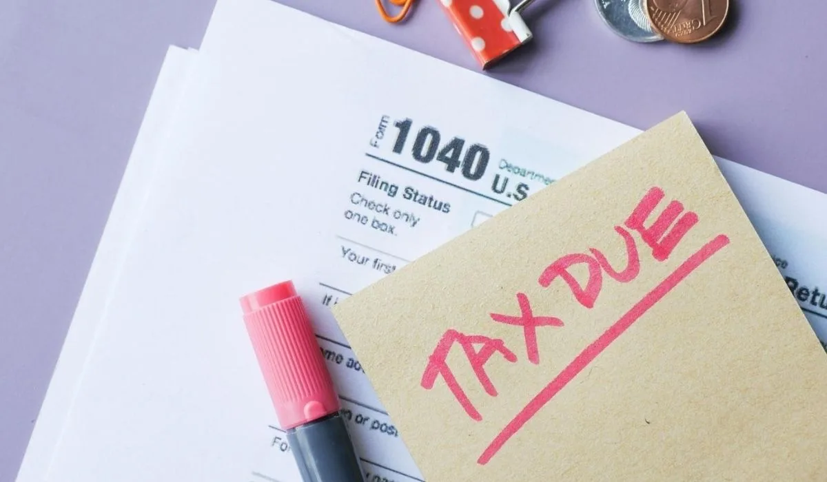 Papel con la palabra "impuestos" y un bolígrafo, simbolizando la declaración de impuestos para inversionistas latinos.