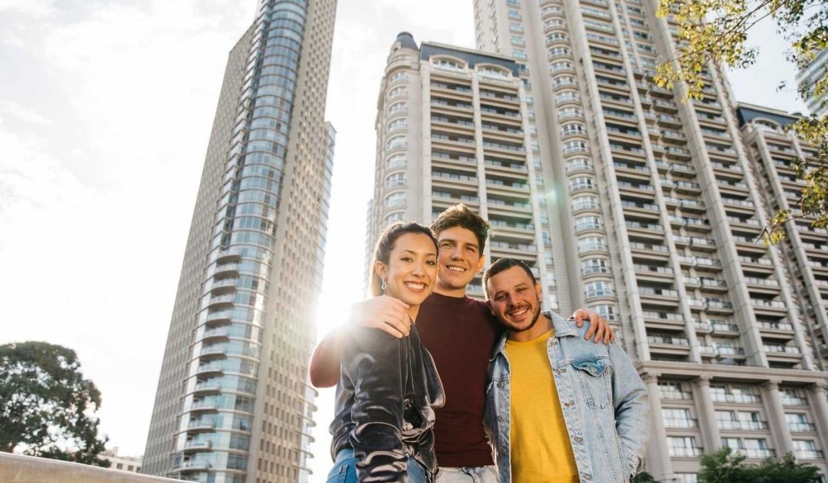 Tres personas de pie frente a altos edificios, representando la inversión en multifamiliares en Orlando.