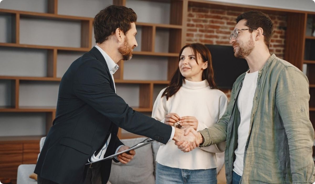A man and woman shake hands with another couple in a cozy living room, celebrating a property closing in Florida.