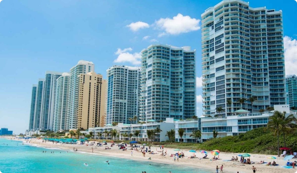 Playa llena de gente con edificios al fondo, representando el destino exclusivo de inversión Sunny Isles.
