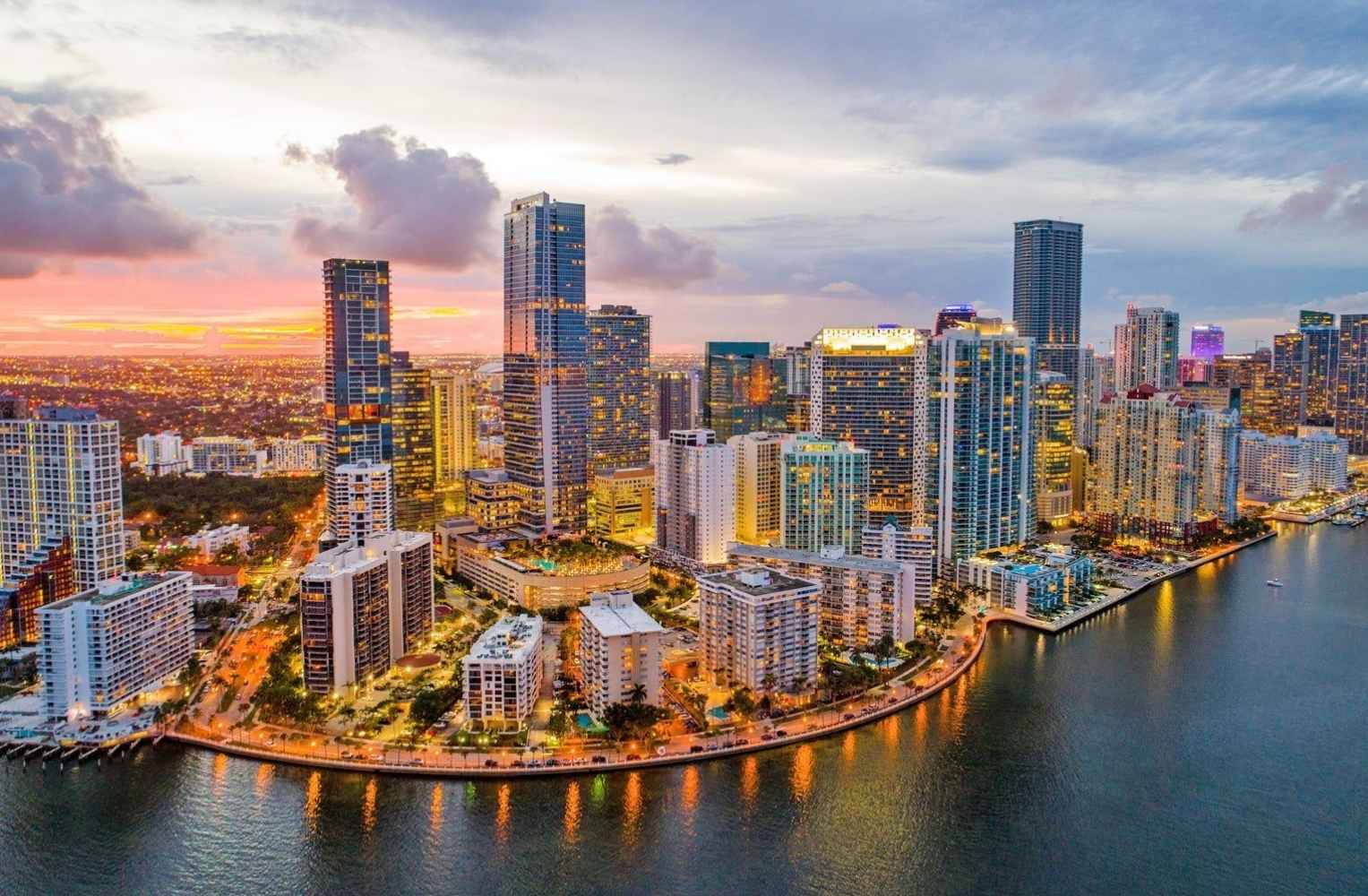 Skyline de Miami al atardecer, con edificios iluminados y un cielo naranja, resaltando la belleza de Brickell.