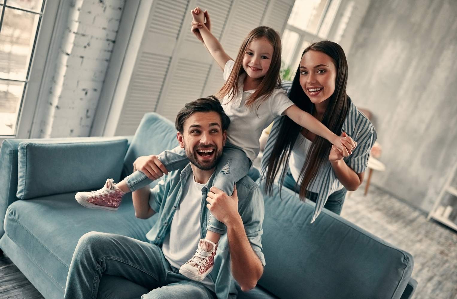 Una familia sonriente sentada en un sofá, disfrutando de un momento juntos con un niño pequeño.