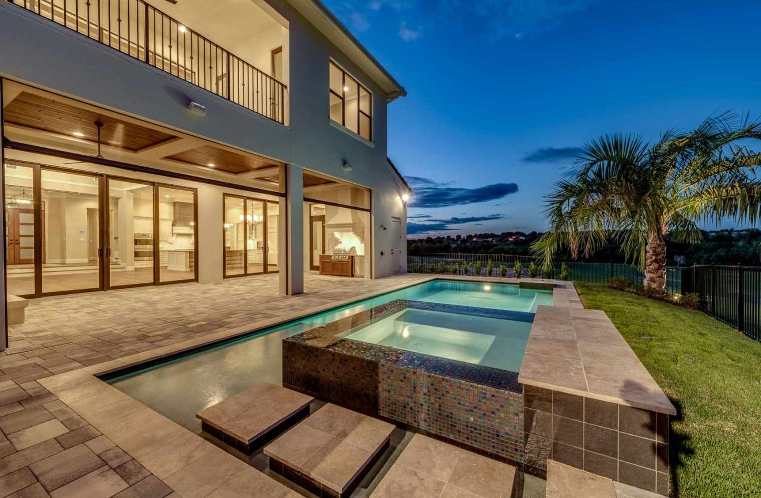 Área de piscina y patio en una casa al anochecer, ideal para disfrutar de propiedades de lujo en Orlando.