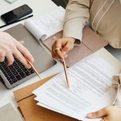 Dos personas revisando documentos en un escritorio, concentradas en su trabajo.