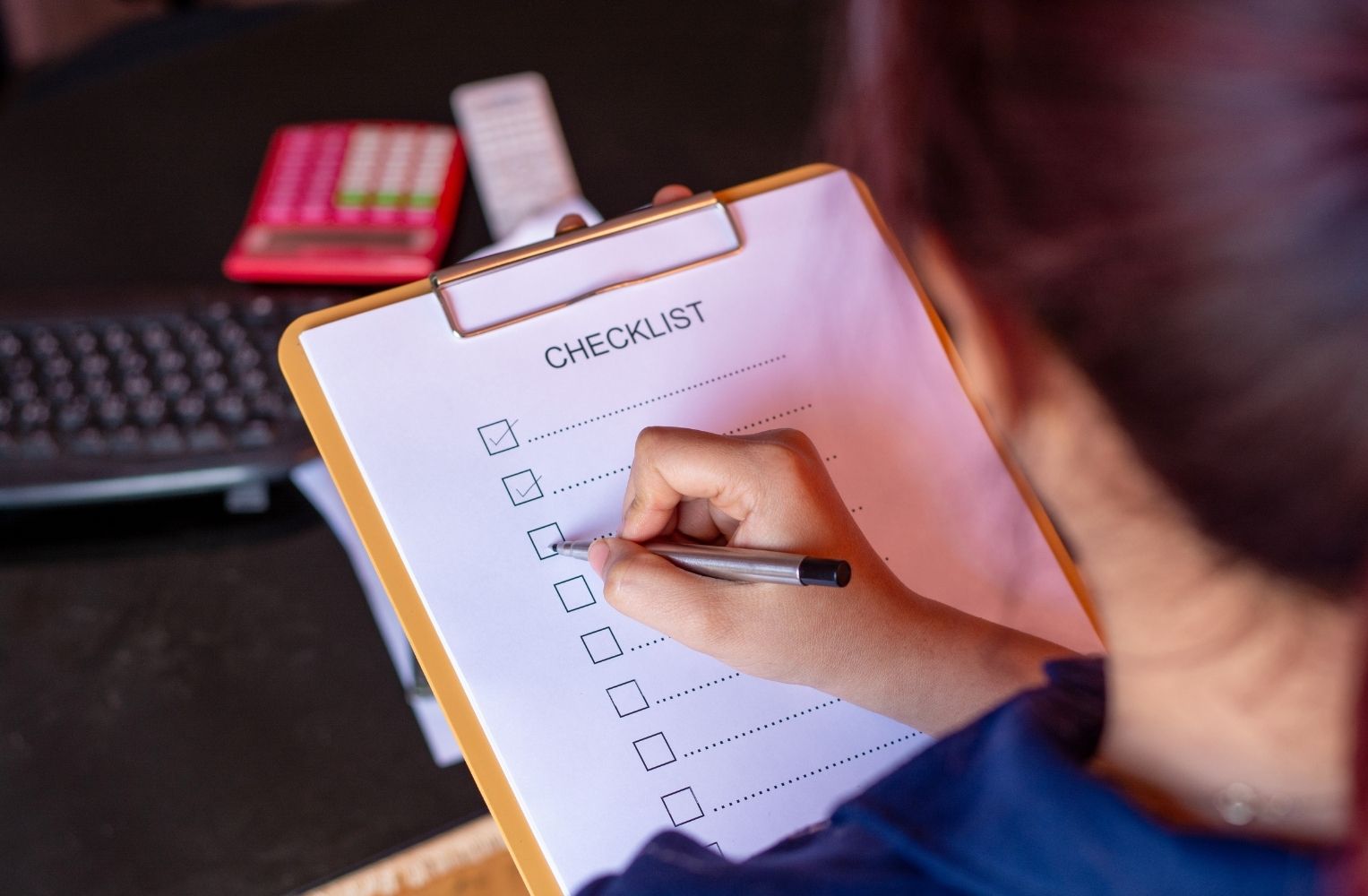 Mujer anotando en un clipboard una lista de tareas.