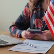 Mujer sentada en un escritorio con una laptop y una bandera