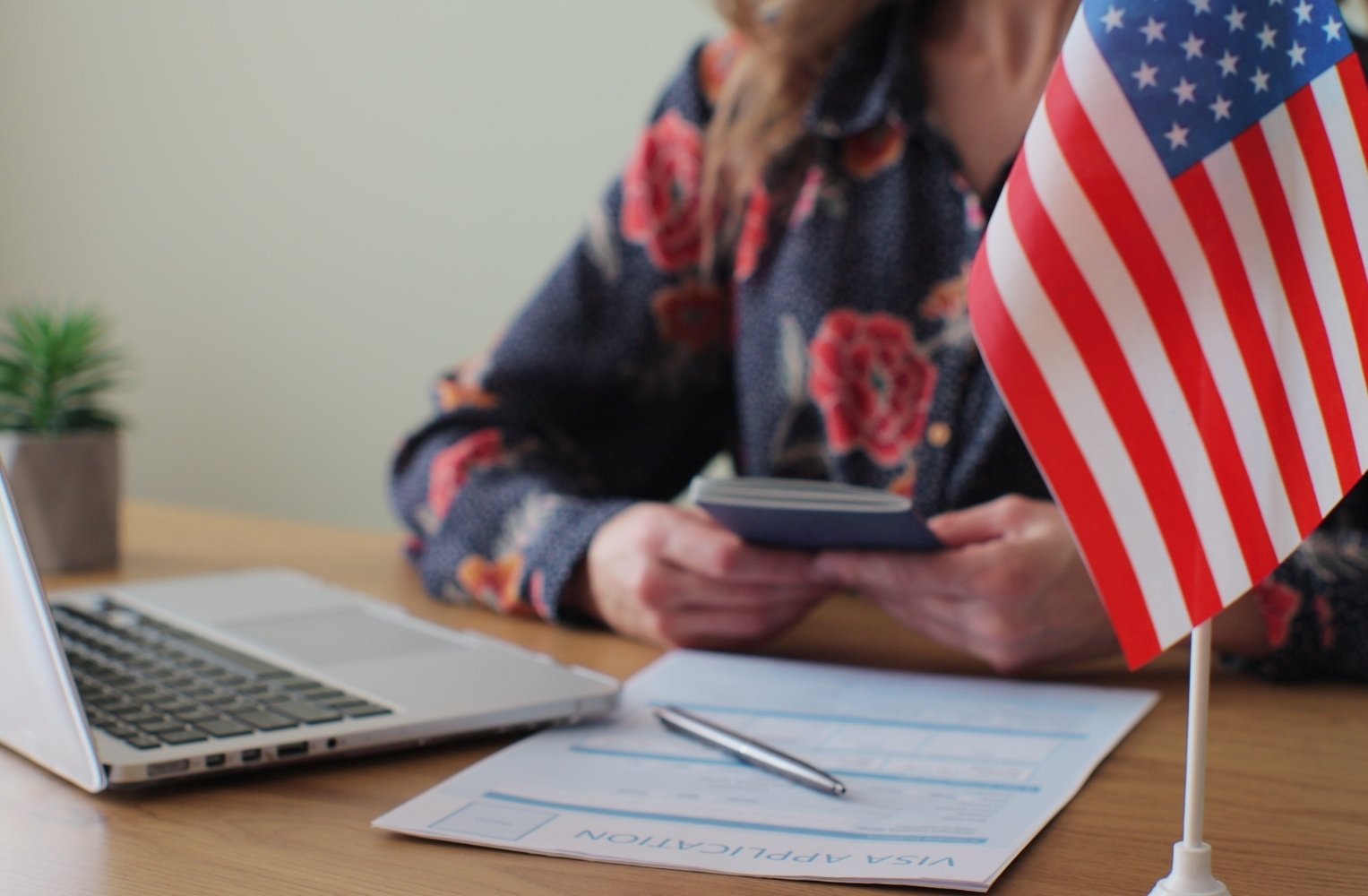 Mujer sentada en un escritorio con una laptop y una bandera