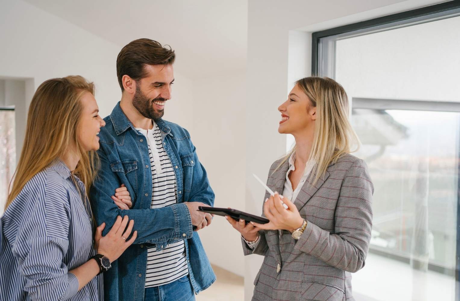 Una pareja conversa con un agente inmobiliario en una oficina.