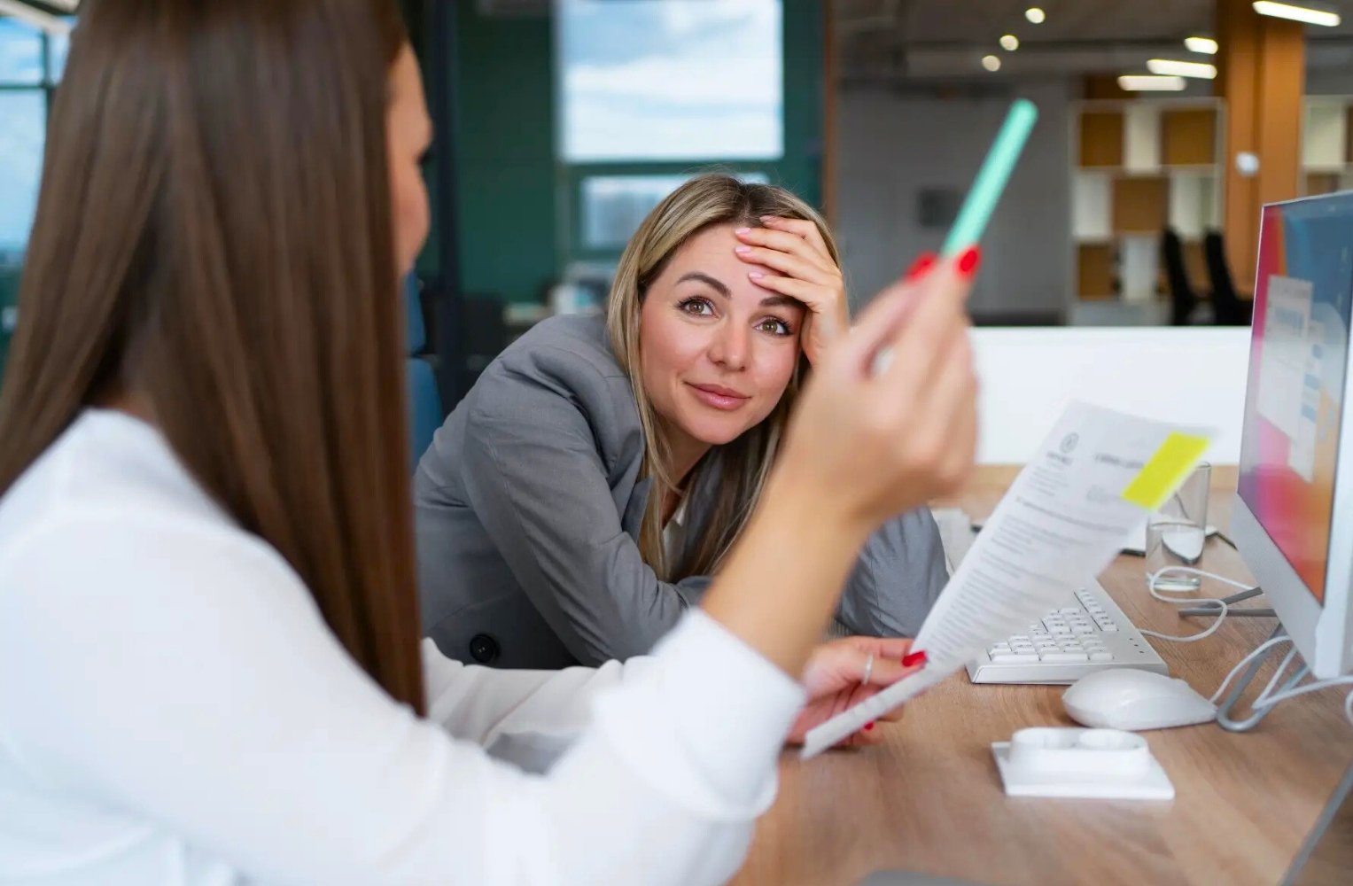 Dos mujeres en una oficina revisando documentos juntas.