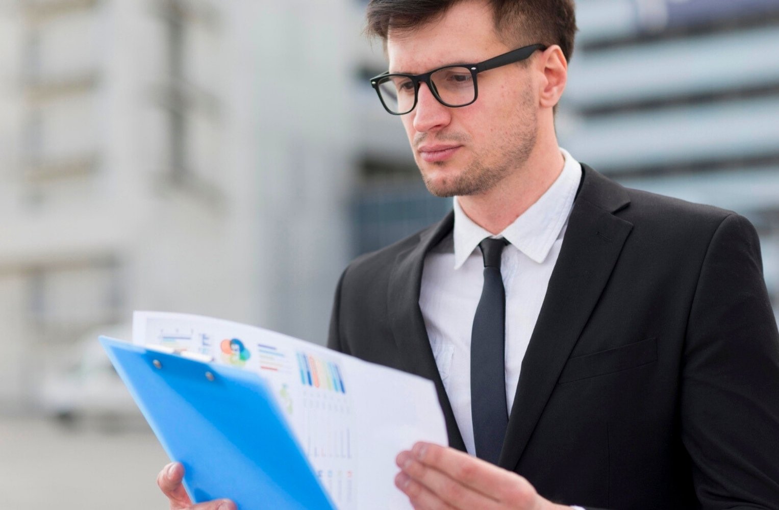 Hombre de negocios con traje y gafas revisando un expediente.