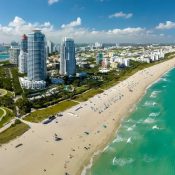 Vista aérea de Miami Beach, mostrando playas, edificios y el océano en un día soleado.