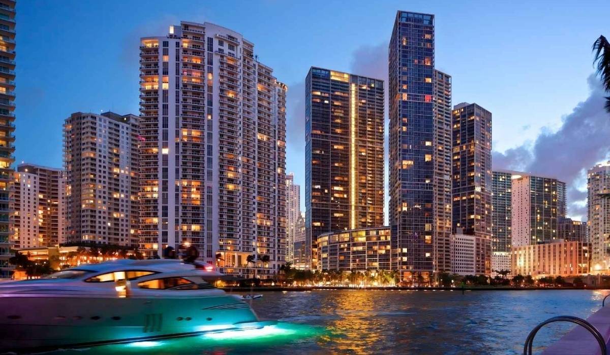 Un barco atracado frente a altos edificios iluminados por la noche.