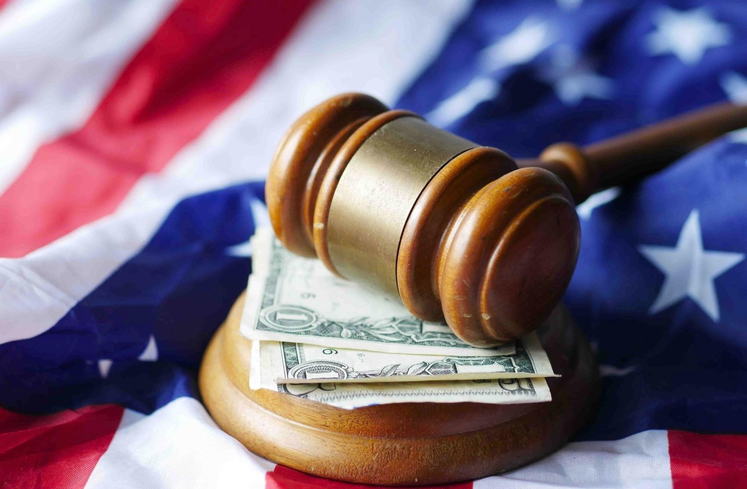 Un mazo de juez y dinero sobre la bandera estadounidense