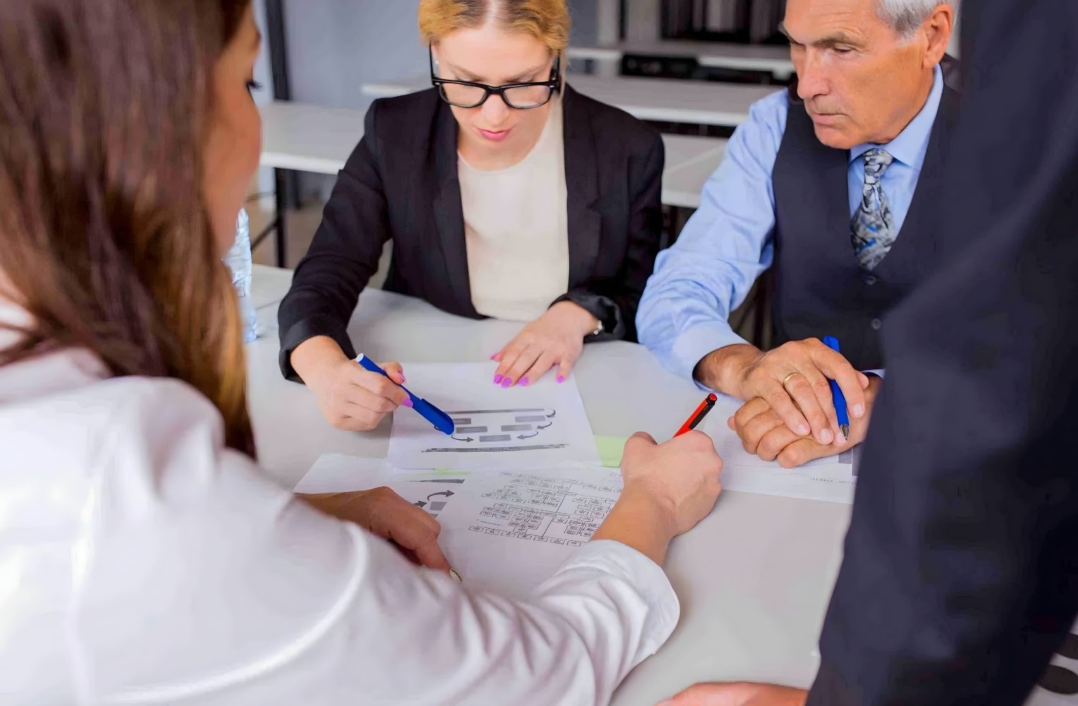 Un grupo de profesionales se sienta alrededor de una mesa en una reunión de trabajo.