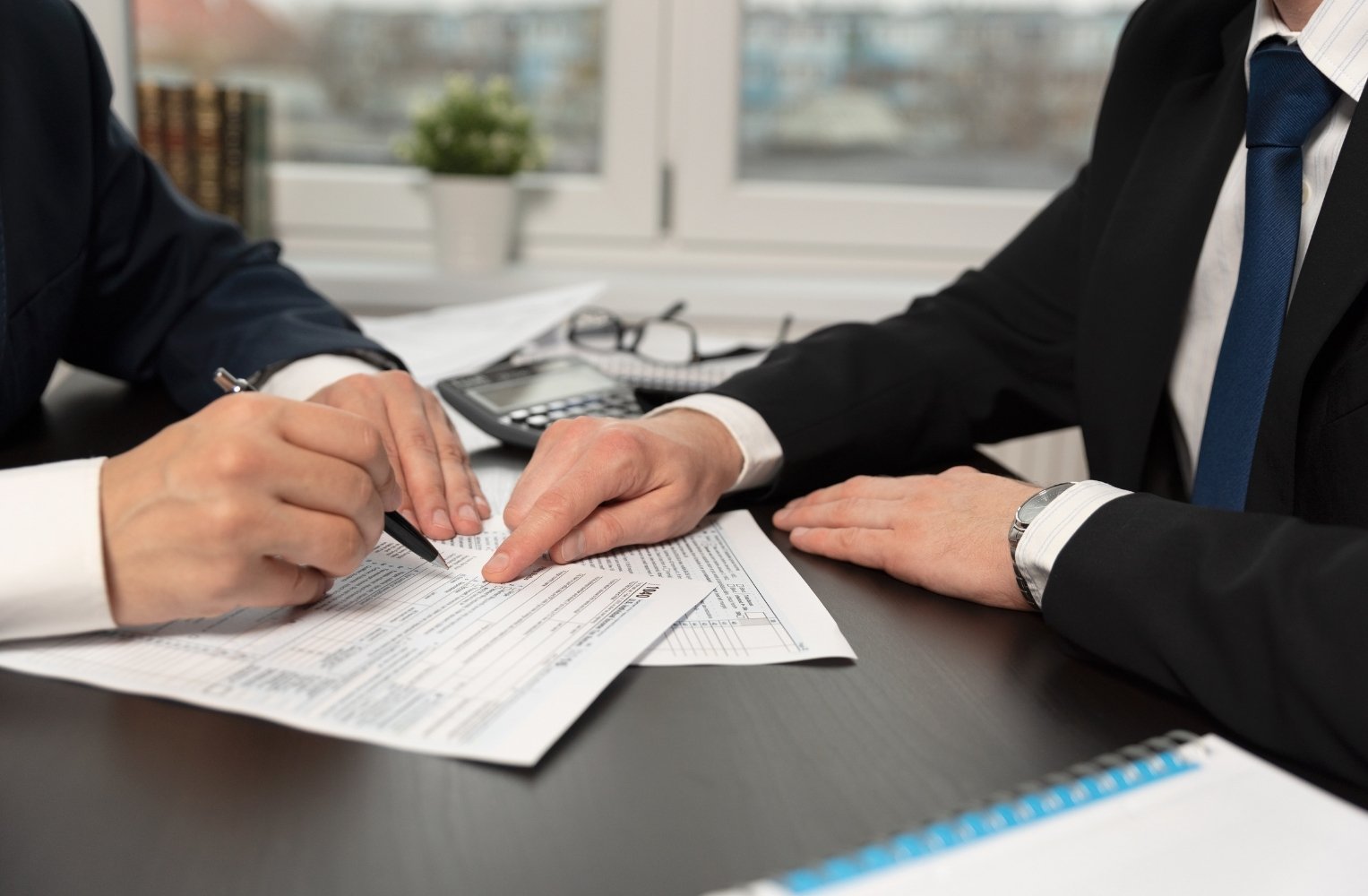 Dos personas de negocios firman documentos en un escritorio.