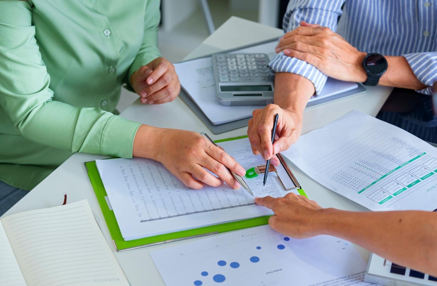 Personas de negocios revisando documentos en un escritorio compartido.