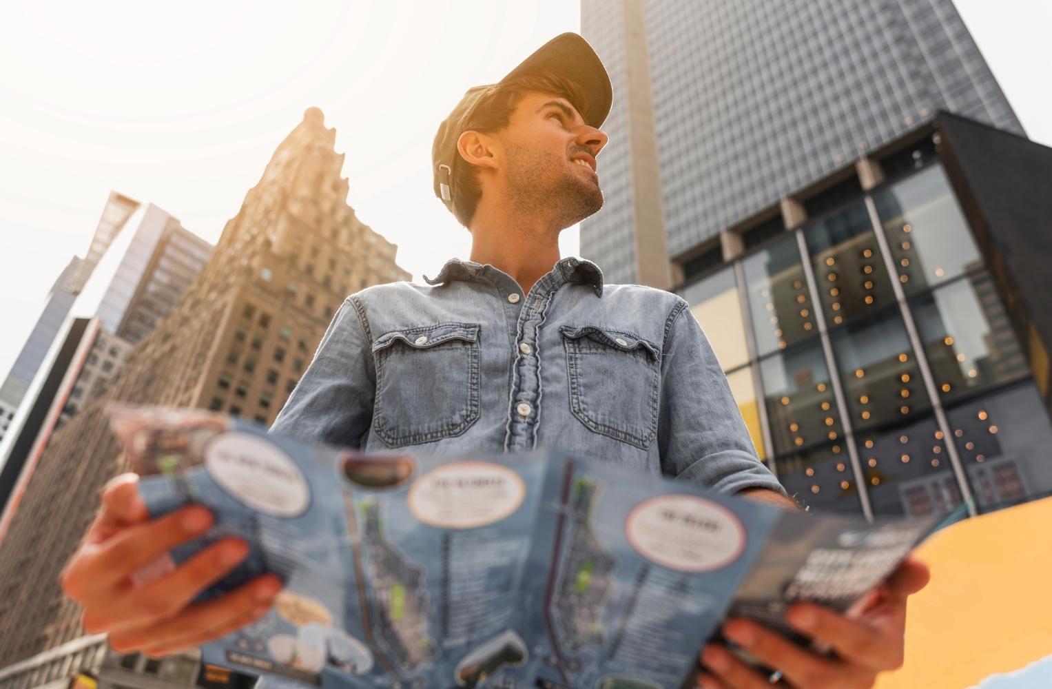 Hombre sosteniendo un mapa frente a una ciudad moderna.