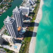 Vista aérea de la playa y edificios en Miami, mostrando la costa y la arquitectura urbana.