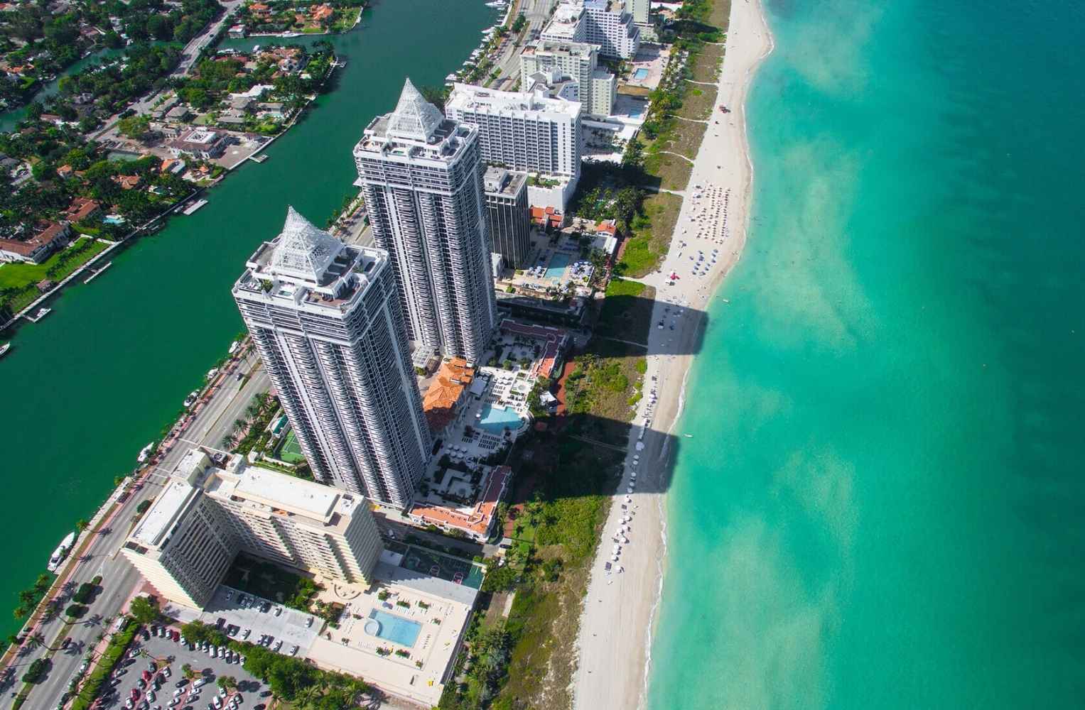 Vista aérea de la playa y edificios en Miami, mostrando la costa y la arquitectura urbana.