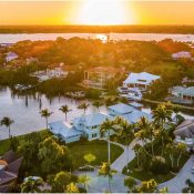 Atardecer dorado sobre mansiones de lujo con embarcaderos privados en una zona costera de Florida.