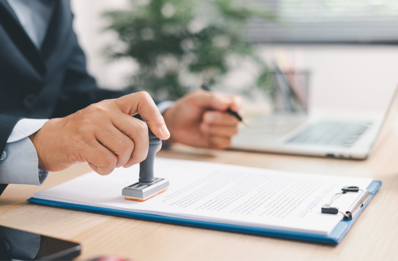 Close-up of a person stamping an official mortgage application document on an office desk.