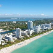 Vista aérea de la costa de Florida con edificios modernos, playas de arena blanca y aguas turquesas.