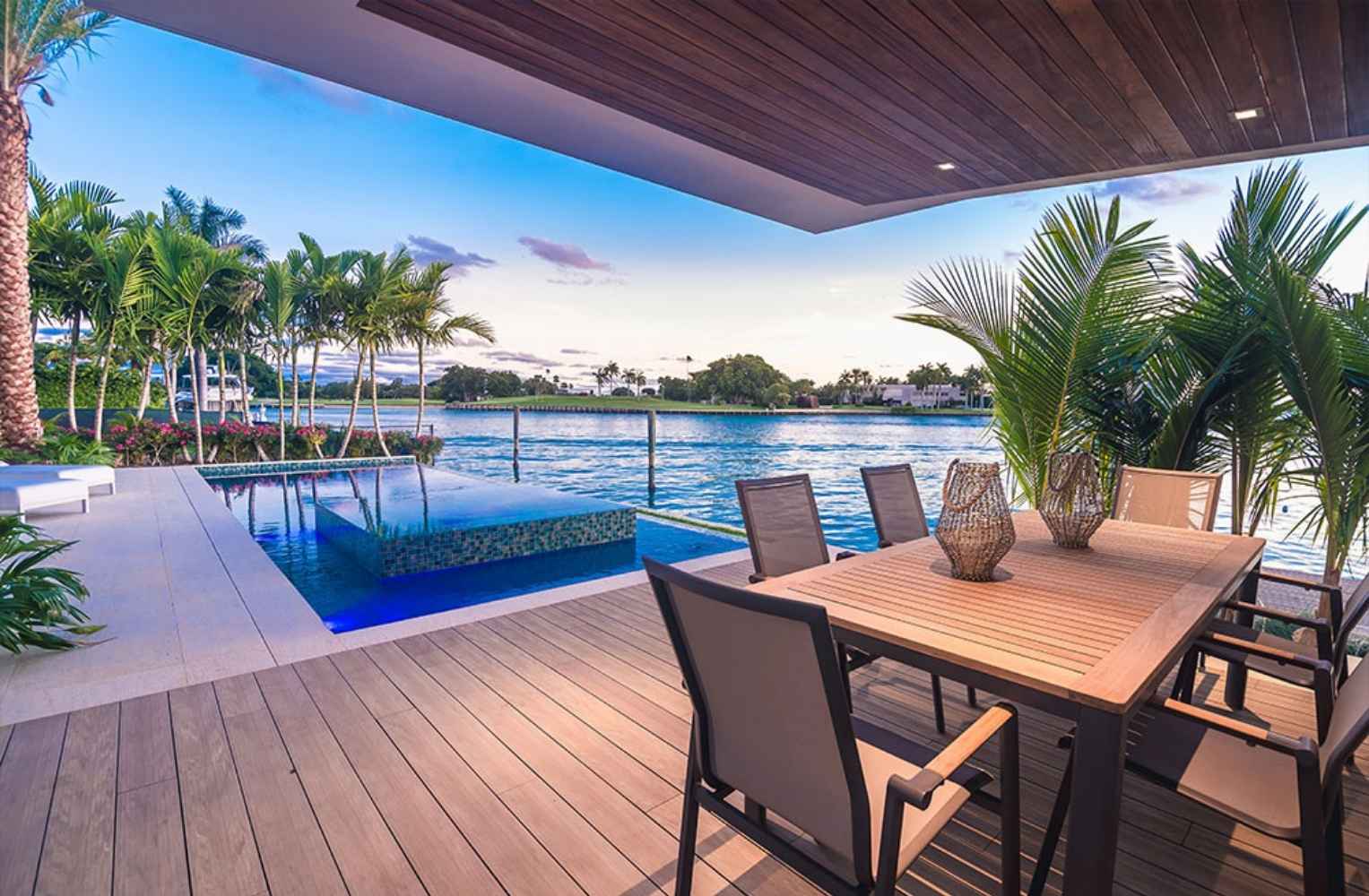 Terraza de una mansión de lujo en Miami con piscina infinita, comedor al aire libre y vista directa al mar.