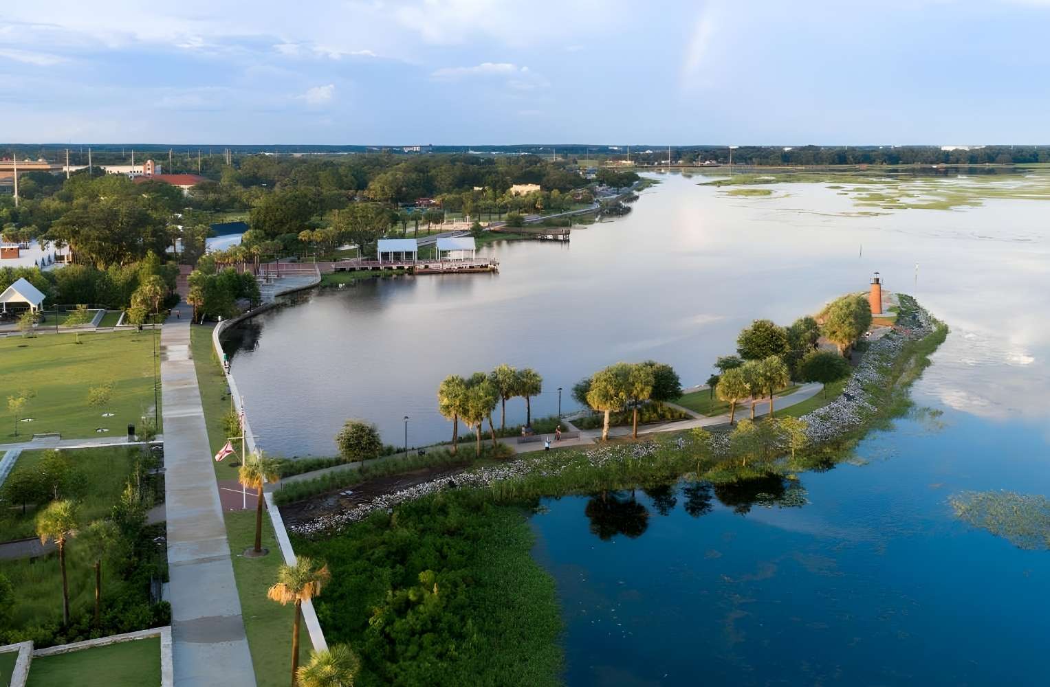 Vista aérea del Lake Baldwin en Orlando, Florida, mostrando senderos para caminar, parques verdes y aguas tranquilas bajo un cielo despejado.